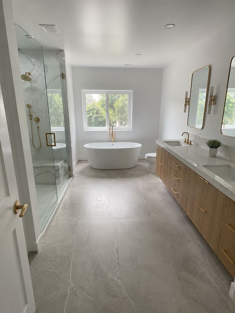 Bathroom looking toward the shower, with double vanity and brass sconces