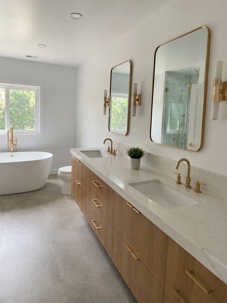 Double vanity in white oak with a quartz top, brass fittings and arched mirrors