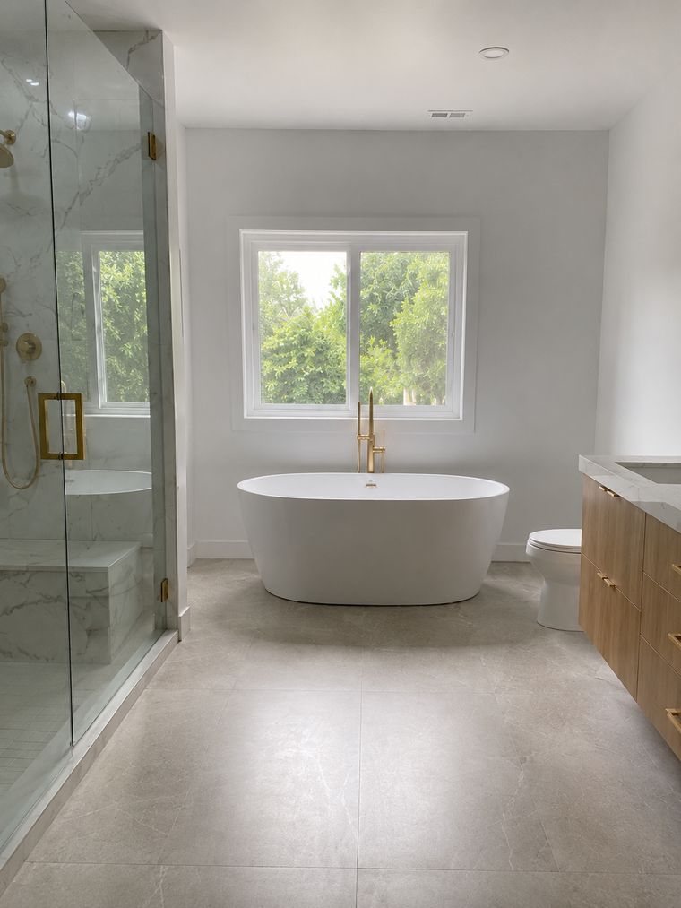 Marble-veined shower wall and bench behind frameless glass